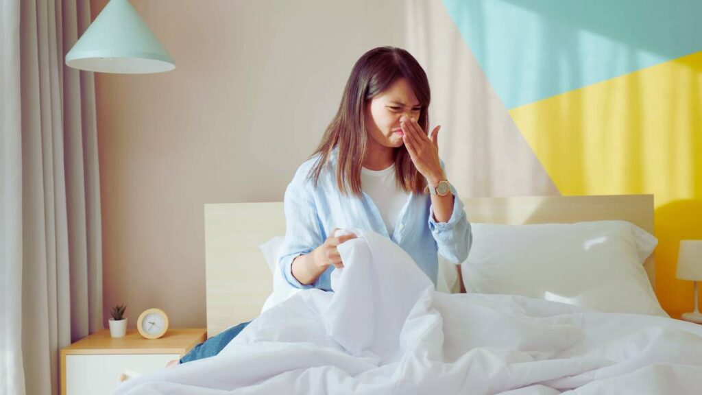 Girl in bed frowning due to bad smell