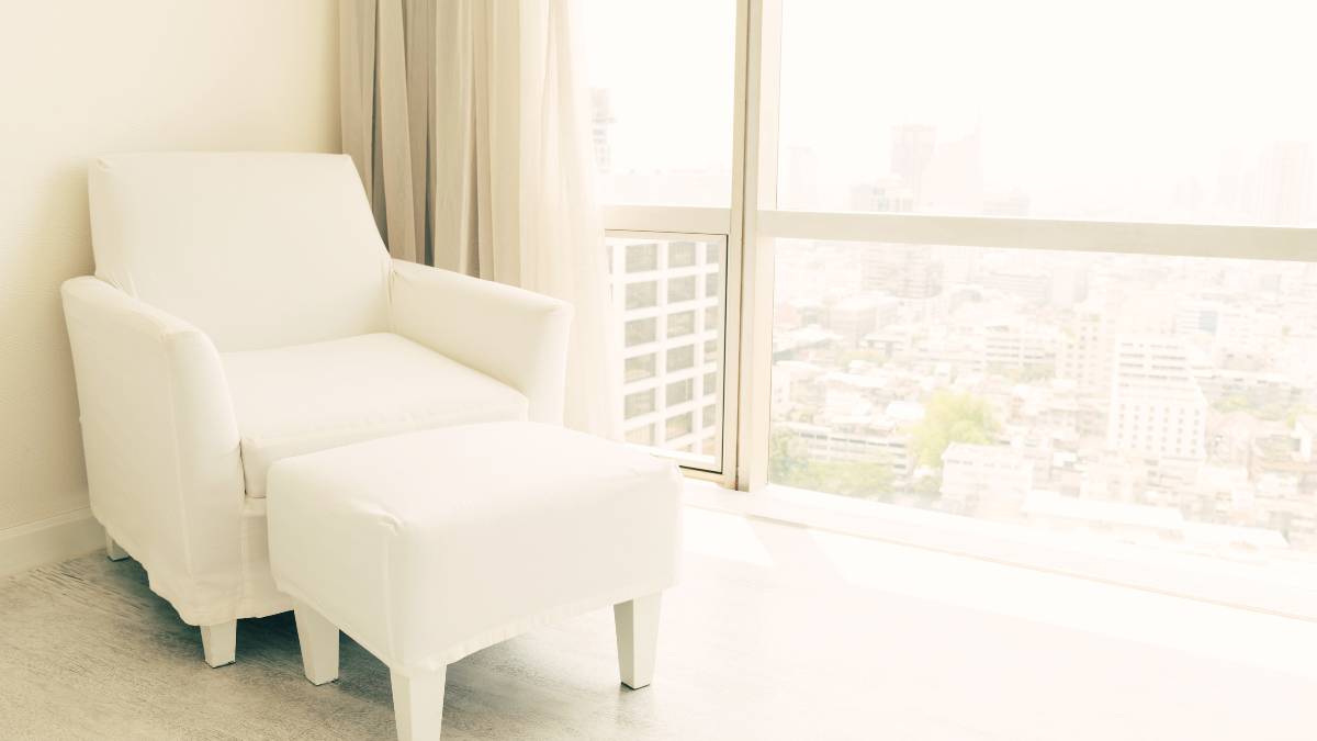 white recliner beside glass window overlooking the city