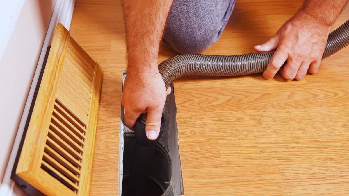 a person inserting a hose in an air duct