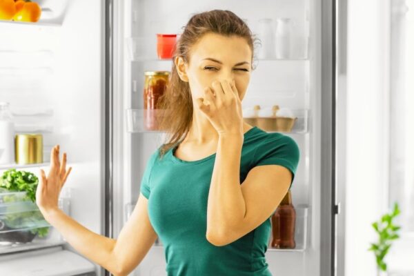 Girl covering her nose due to bad smell in the kitchen.