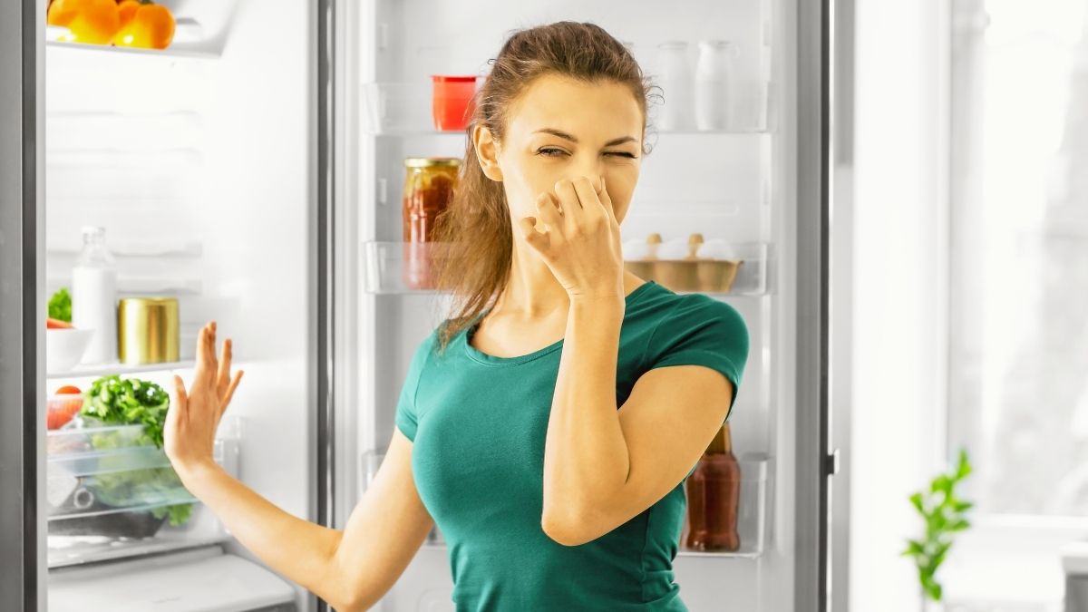 Girl covering her nose due to bad smell in the kitchen.